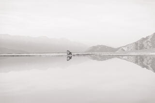 An excavator sits idle at the edge of large, flooded pond, Owens Lake