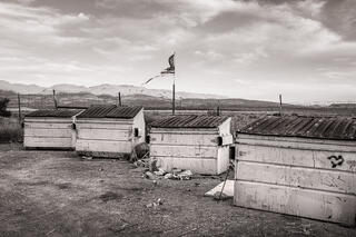 Torn American flag flying over a set of garbage dumpsters